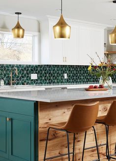 a kitchen island with three stools in front of it and green tile backsplash