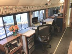 an office area with desks, chairs and windows