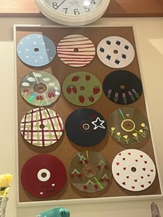 a clock mounted to the side of a wall with many different designs on it's face