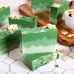 soap bars with flowers on them sitting on a counter next to a bowl and cutting board