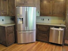 a metallic refrigerator freezer sitting inside of a kitchen next to wooden cabinets and drawers