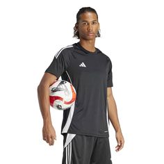 a young man holding a soccer ball in his right hand and posing for the camera