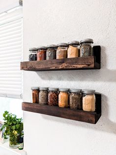 two wooden shelves filled with jars and spices on top of a white wall next to a potted plant