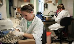 two women in white lab coats are working on an egg carton at the laboratory