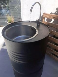 a large black barrel with water running from it's faucet to the side