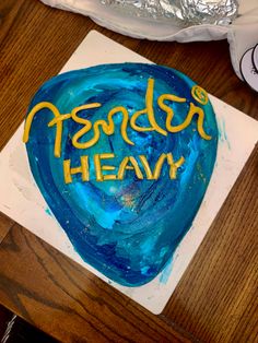 a blue and yellow cake with the words fender's heavy on it sitting on top of a wooden table