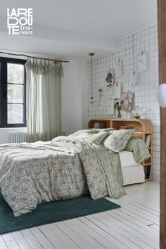 a bedroom with white walls and wood flooring has a green rug on the floor