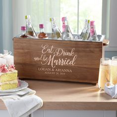 a wooden box filled with cake and drinks on top of a table next to two glasses