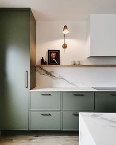 a kitchen with green cabinets and marble counter tops