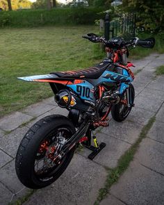 a blue and orange dirt bike parked on the sidewalk