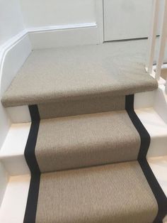 a set of carpeted stairs leading up to a white door with black stripeing