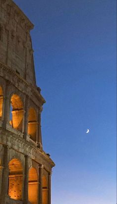 the moon is setting behind an ancient building