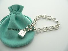 Offered for sale is a wonderful and super cute Tiffany and Co. Sterling Silver 1837 Cube / Box Charm bracelet.   The piece is made from substantial and bright Tiffany silver, and yet retains a very feminine feel to it.  Attached to its very substantial and bright Tiffany Silver charm bracelet is a super Cool 1837 Cube Padlock charm.  The Gift Box padlock charm is permanently attached to the bracelet - so you will not ever have the risk of losing the charm!  It is a classic Tiffany piece that Tiffany Charm Bracelets Tiffany & Co., Tiffany Inspired Jewelry Sterling Silver, Rectangular Bracelet With Box Clasp For Gift, Rectangular Bracelet With Box Clasp As Gift, Designer Rectangular Bracelets As Gift, Luxury Rectangular Bracelet Gift, Luxury Rectangular Bracelet As Gift, Tiffany And Co Bracelet, Tiffany T