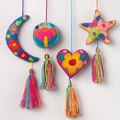 three colorful handmade ornaments hanging from strings with tassels and flowers on them