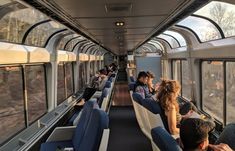 people are sitting on the train and looking out the windows at the trees in the distance