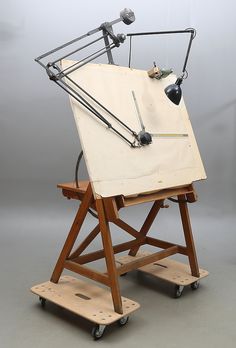 an old fashioned desk with a lamp on it's top and two wheels attached to it