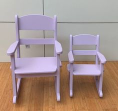 two purple chairs sitting on top of a wooden floor next to each other in front of a white wall