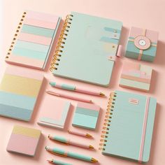 various stationery items are arranged on a pink and blue surface with gold trimmings