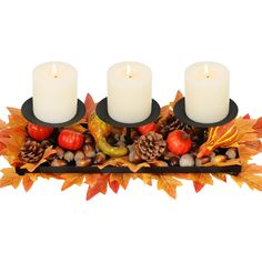 three candles sitting on top of a tray filled with autumn leaves