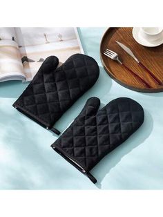 two oven mitts sitting on top of a table next to a plate and fork