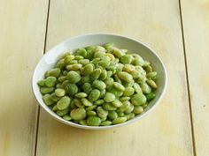 a white bowl filled with green beans on top of a wooden table