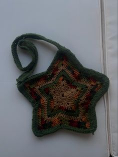 a green crocheted star ornament hanging from a white wall