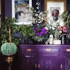 there are many plants on the dresser in this room, and one is painted purple