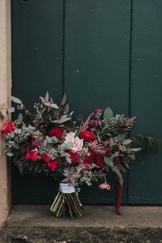 a bouquet of flowers sitting in front of a green door