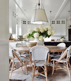 a dining room table and chairs with flowers in the center surrounded by rugs on the floor