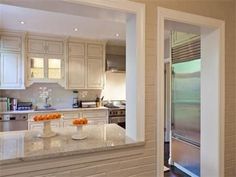 a kitchen with white cabinets and marble counter tops