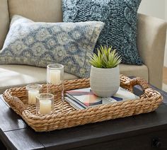 a wicker tray with candles on it in the middle of a living room area