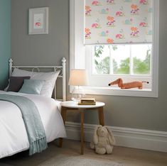 a bed room with a neatly made bed and a small table next to the window