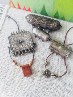 Bedouin silver-amult convulut of different sizes & shapes: Silver Hirz hallmarked with knobs.70 gr. heavy 12 cm long. 2. decorated with silver wire, 7 cm long, 25 gr. heavy.3. Rashaida Bedouin Hirz decorated with silver wire / plates, old Yemeni handicraft with bells as pendant.7 cm wide. 4. Elegant silver Hirz 27 gr. Heavy. 5. small leather amulet + small, very nicely cleaned amulet Yemeni Jewelry, Decorative Metal Sheets, Kuchi Jewelry, Talisman Jewelry, Ribbon Jewelry, Casting Jewelry, Handcrafted Artisan Jewelry, Ancient Jewelry, Pattern Dress