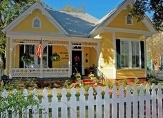 a yellow house with a white picket fence