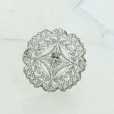 "Edwardian Platinum and Diamond Brooch of circular form with filigree arch decoration. Diamond Halo and diamond set leaf decoration Circa 1925, 1.5\" round, 14.31 grams Stock # BB595RA22 This listing contains photographs of the actual item you will receive. Our items are in excellent condition with little or no signs of wear and many are one of a kind pre-owned estate finds. Please look closely at the pictures in this listing as they are part of the product description. Please read the descripti Ornate White Gold Diamond Brooches, Antique White Gold Filigree Brooch, Luxury Vintage Diamond White Brooches, Victorian Hallmarked Diamond Brooches, Vintage Diamond Brooches Hallmarked, Leaf Decoration, Arch Decoration, Diamond Brooch, Leaf Decor