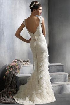 a woman in a wedding dress standing on some steps with her back to the camera