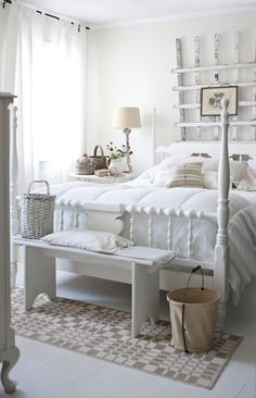 a white bed sitting in a bedroom next to a window