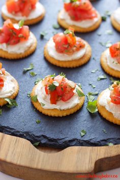 small crackers with tomatoes and cream cheese on them are arranged on a baking sheet