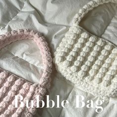 two crocheted purses sitting on top of a white bed next to each other