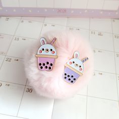 two pink and purple hair clips sitting on top of a white table next to a calendar