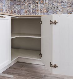 an empty cabinet in a kitchen with tile on the wall and wood flooring around it