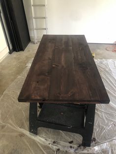 a wooden table sitting on top of a plastic covered floor