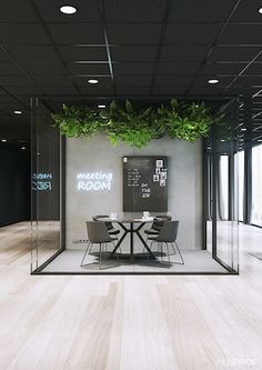 a meeting room with glass walls and plants growing on the wall