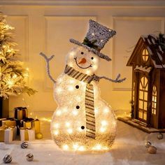 a lighted snowman in front of a christmas tree