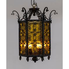 a light hanging from the ceiling with wrought ironwork and yellow glass shades on it