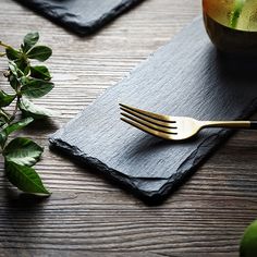 a fork on top of a black napkin next to a bowl of fruit and leaves