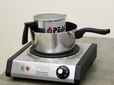 a stainless steel pot sitting on top of a burner with a black handle next to it