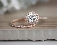 a diamond ring on top of a piece of wood with white flowers in the background