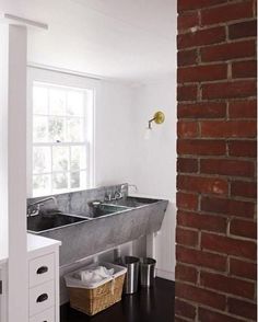 a kitchen sink sitting under a window next to a brick wall