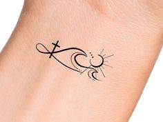 a small tattoo on the wrist of a person with a cross and sun behind it